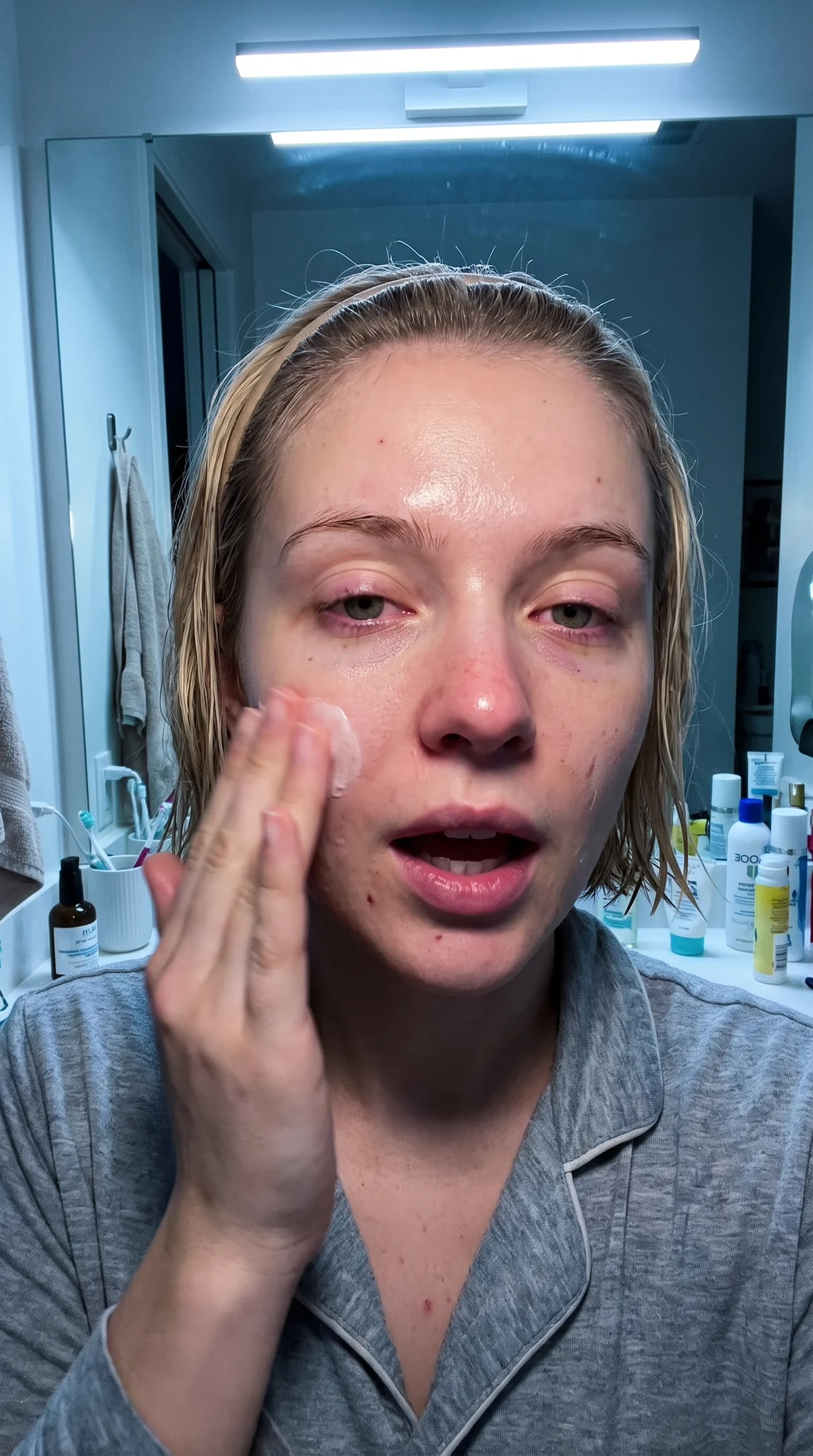 Woman applying skincare in a bathroom reference frame
